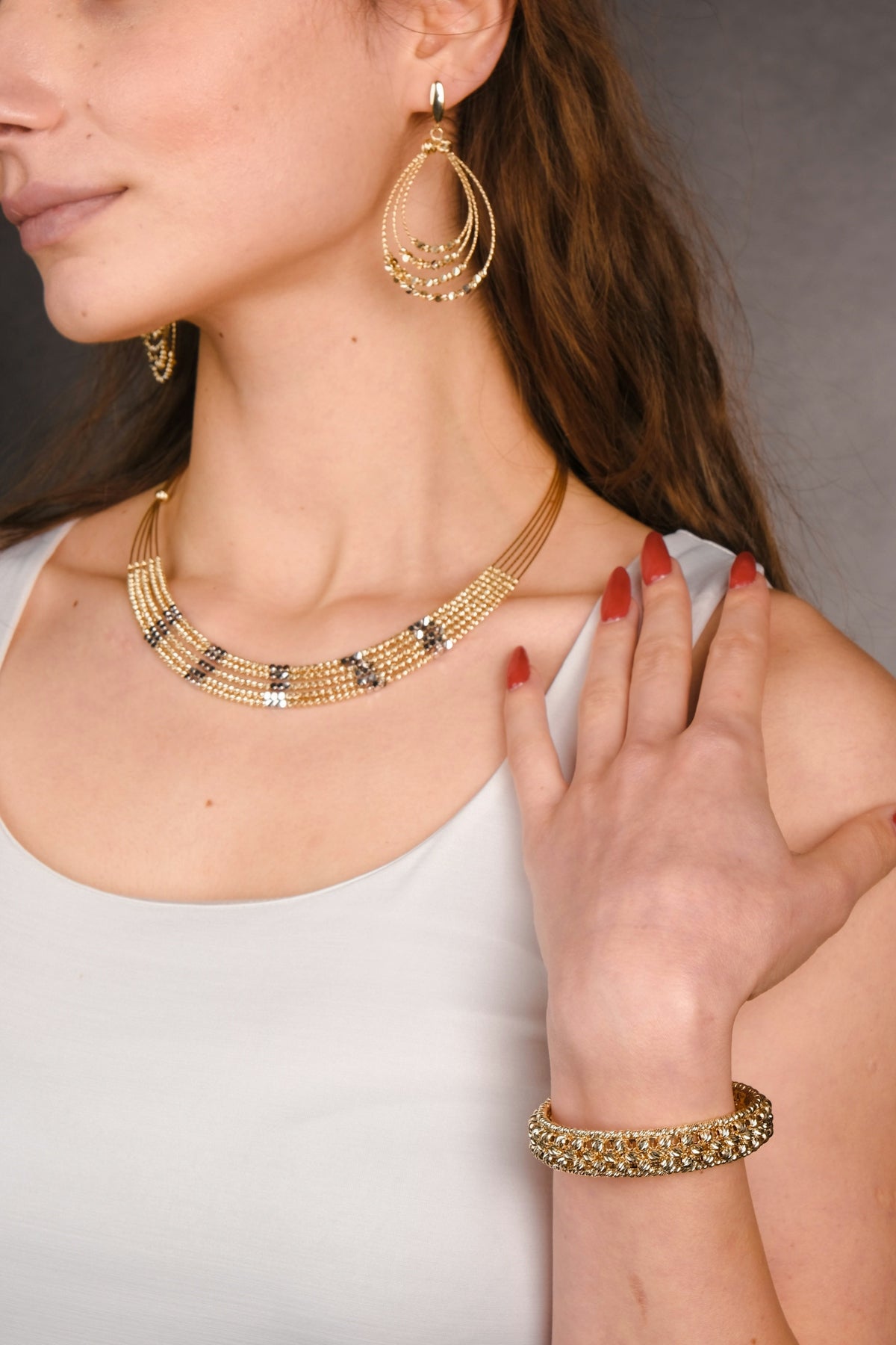 A woman wearing a white top and gold jewelry