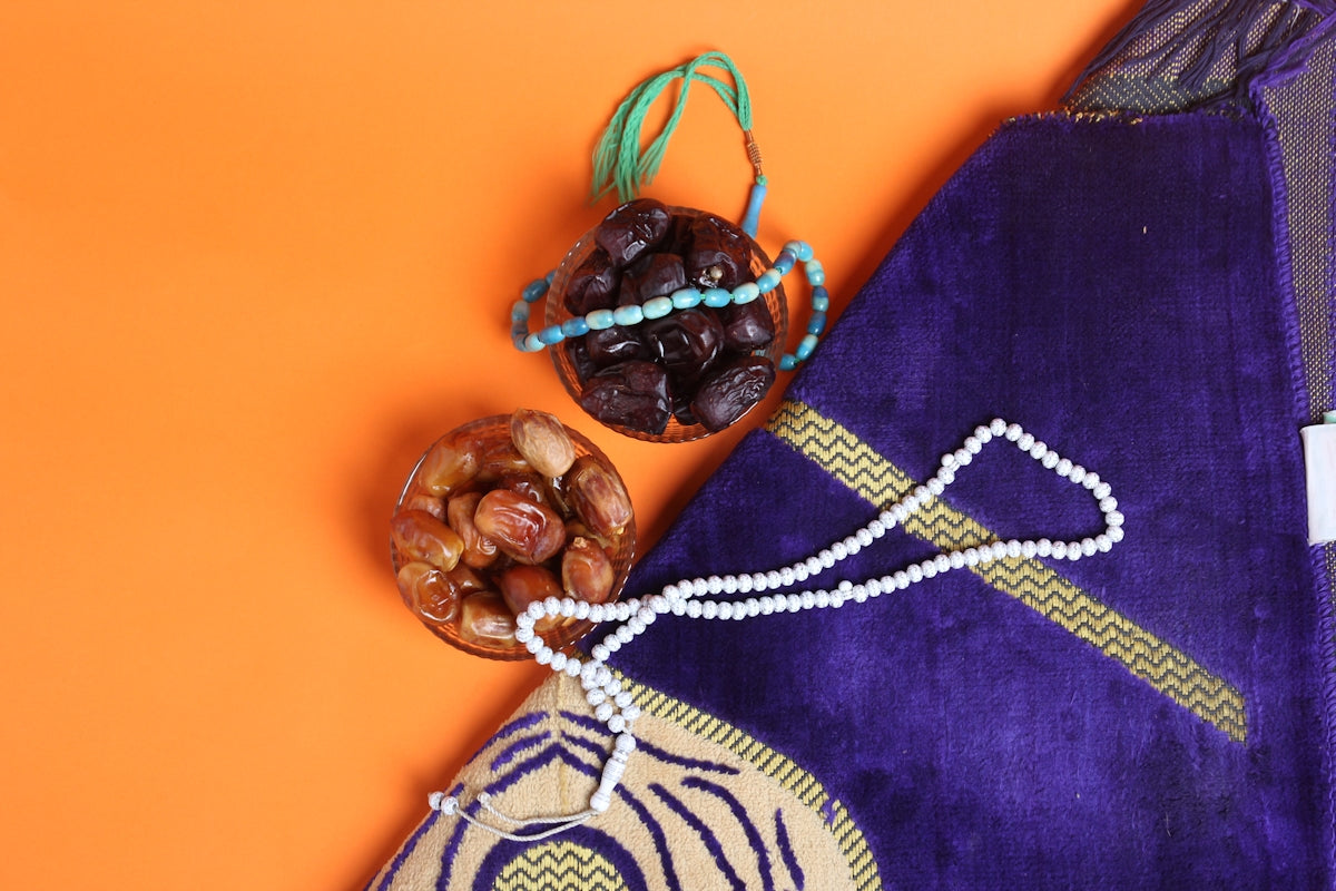 a purple bag with a beaded necklace next to a bowl of nuts