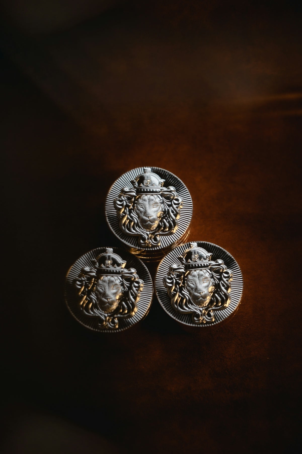three metal buttons with a lion head on them