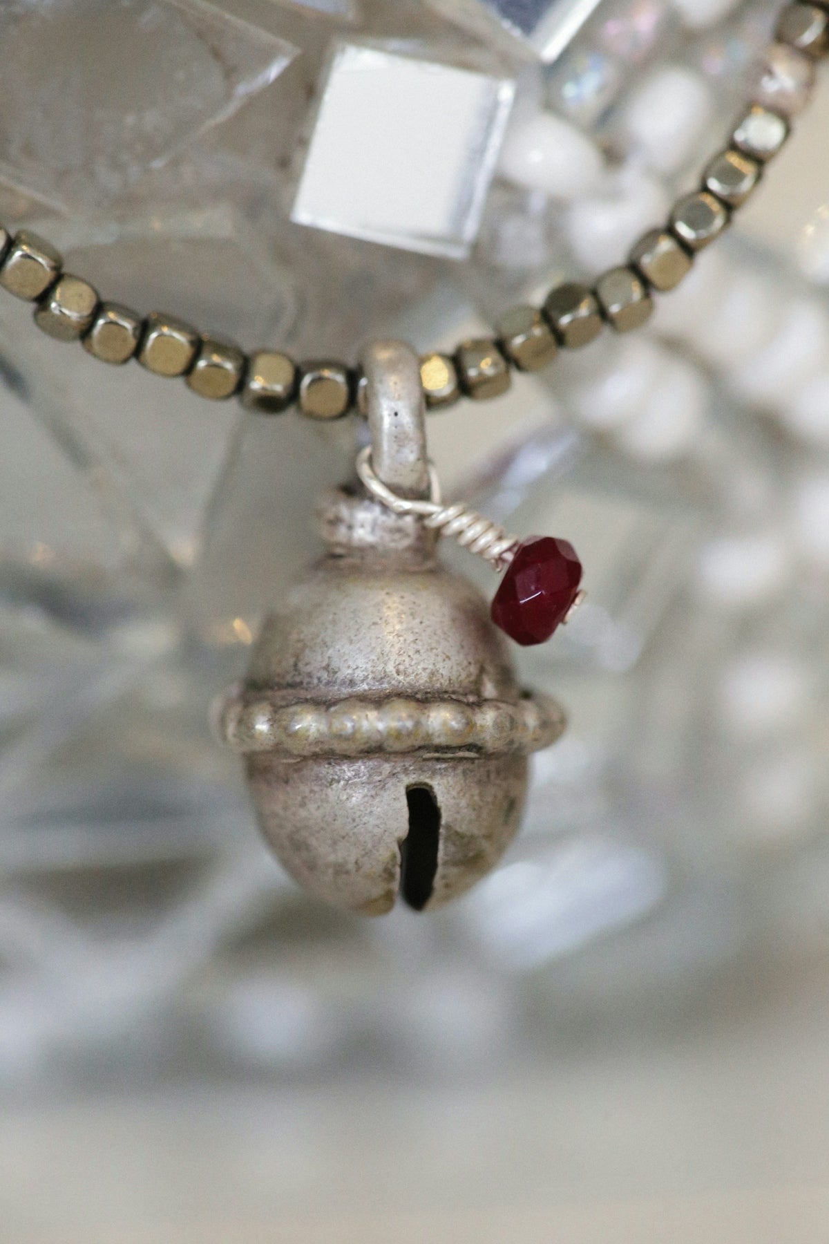 a silver bell with a red bead hanging from it