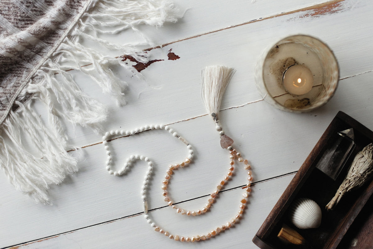 a white beaded necklace and a candle on a table