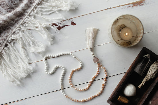 a white beaded necklace and a candle on a table