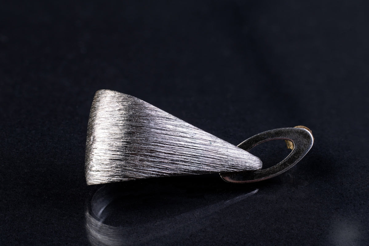 a silver ring with a silver tip on a black surface
