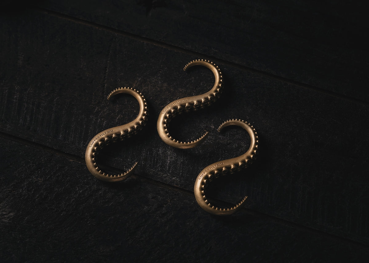 a pair of gold earrings sitting on top of a table