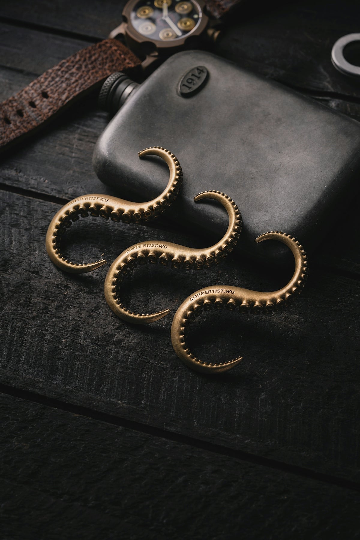 a pair of gold octopus earrings sitting on top of a wooden table