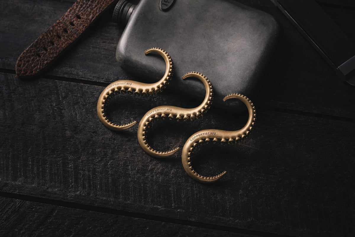 a pair of gold earrings sitting on top of a wooden table