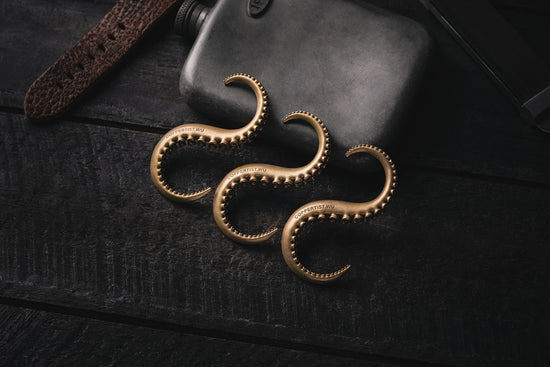 a pair of gold earrings sitting on top of a wooden table
