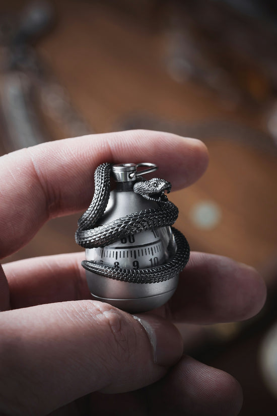 a person holding a silver ring with a snake on it