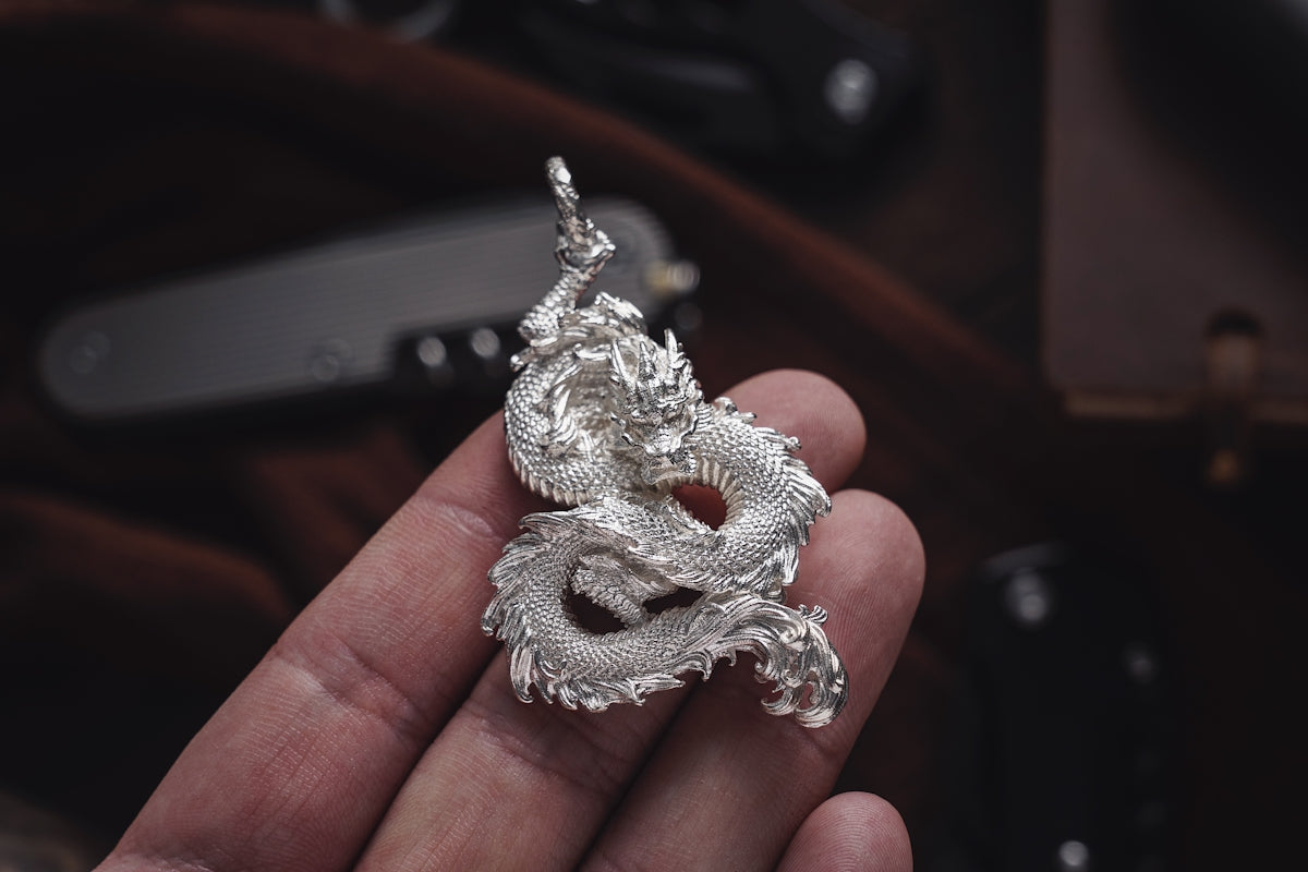 a person holding a silver dragon ring in their hand