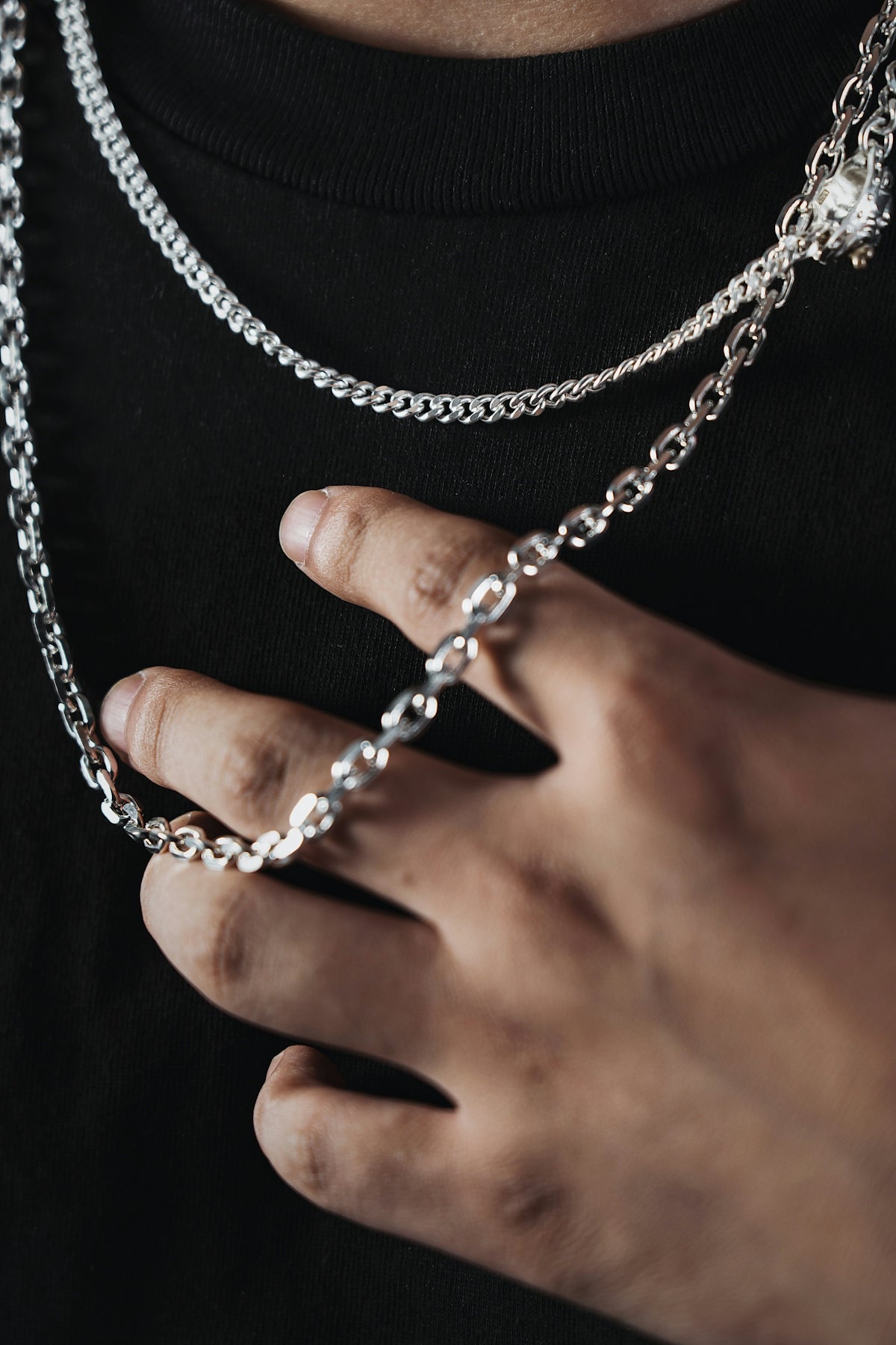 a person wearing a black shirt holding a silver chain