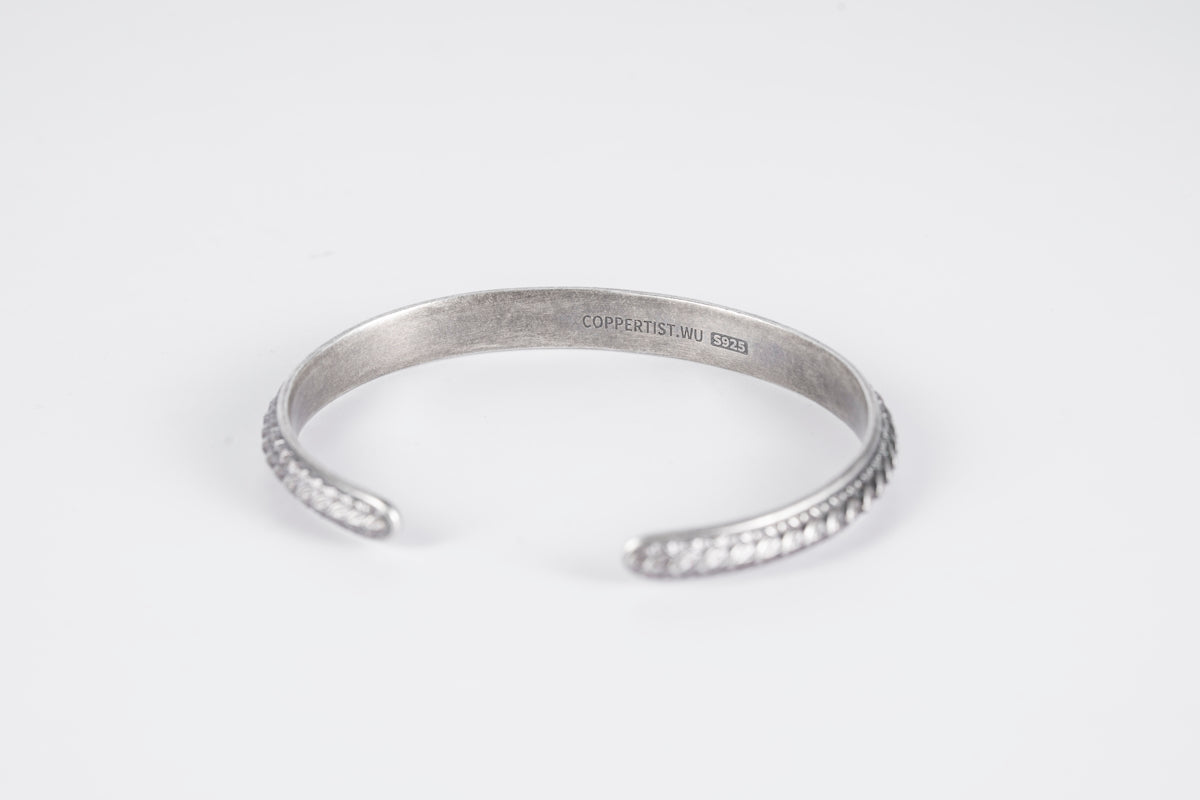 a close up of a silver bracelet on a white background