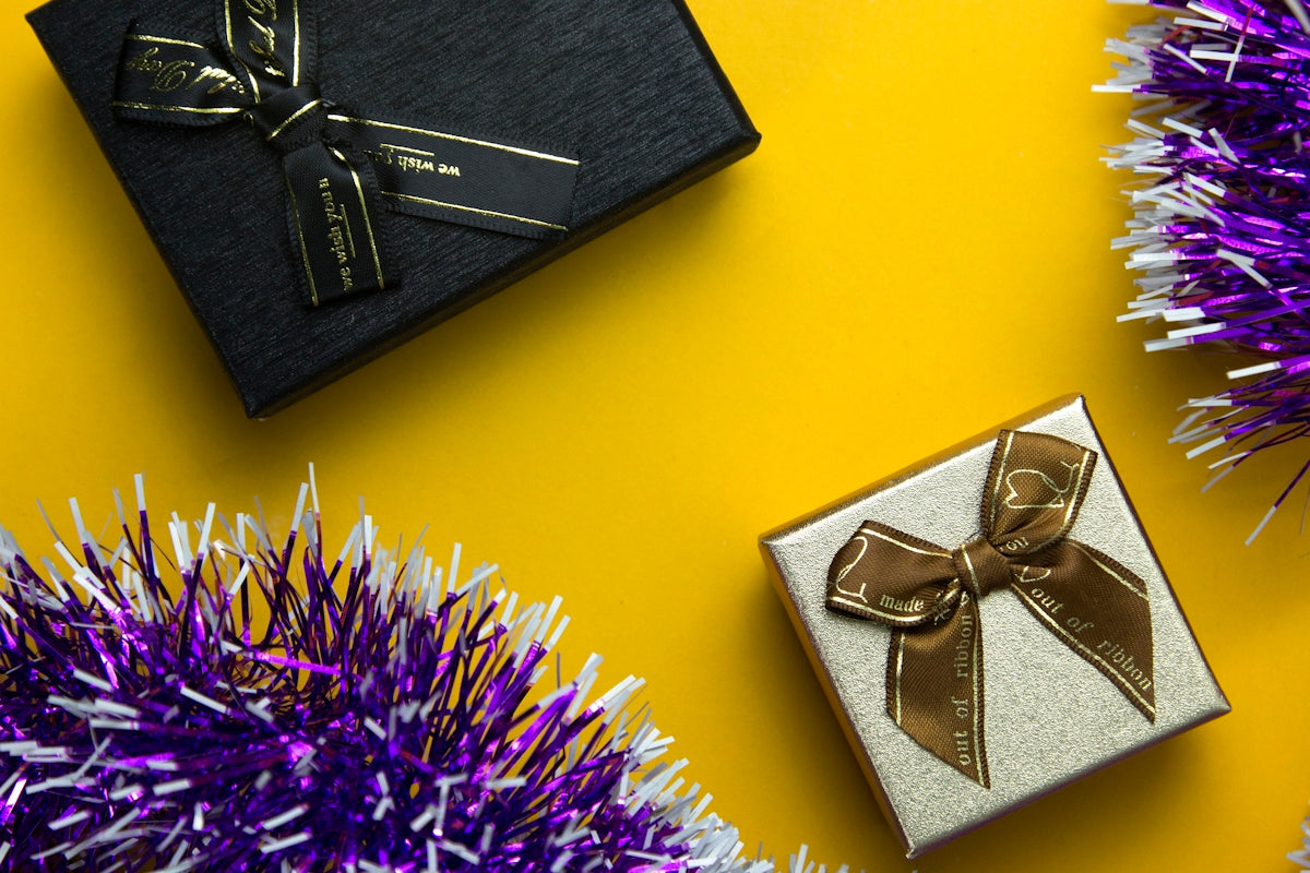 a black box with a gold bow and a purple tinsel