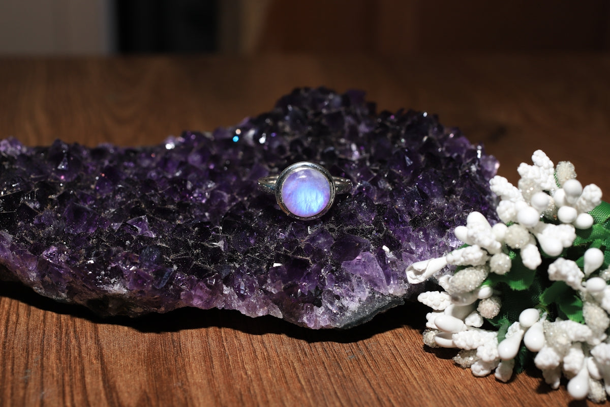 a ring sitting on a rock next to a flower