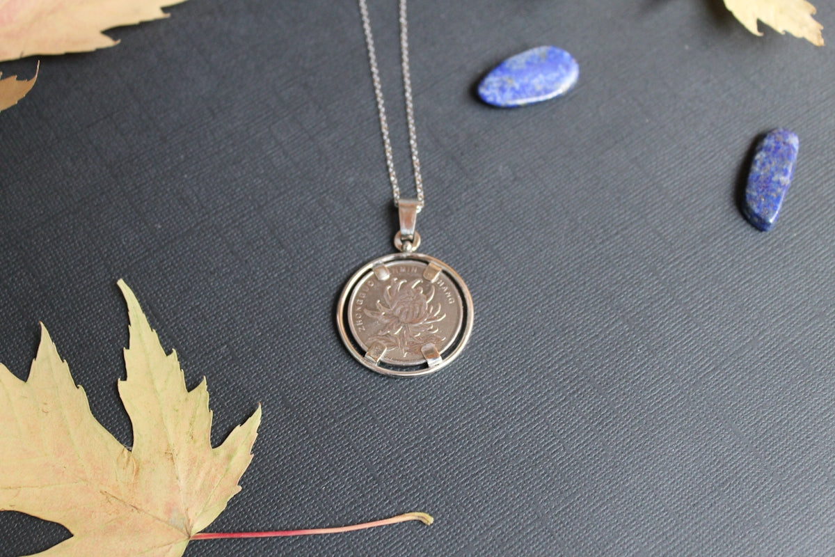 a necklace with a coin sitting on top of a table