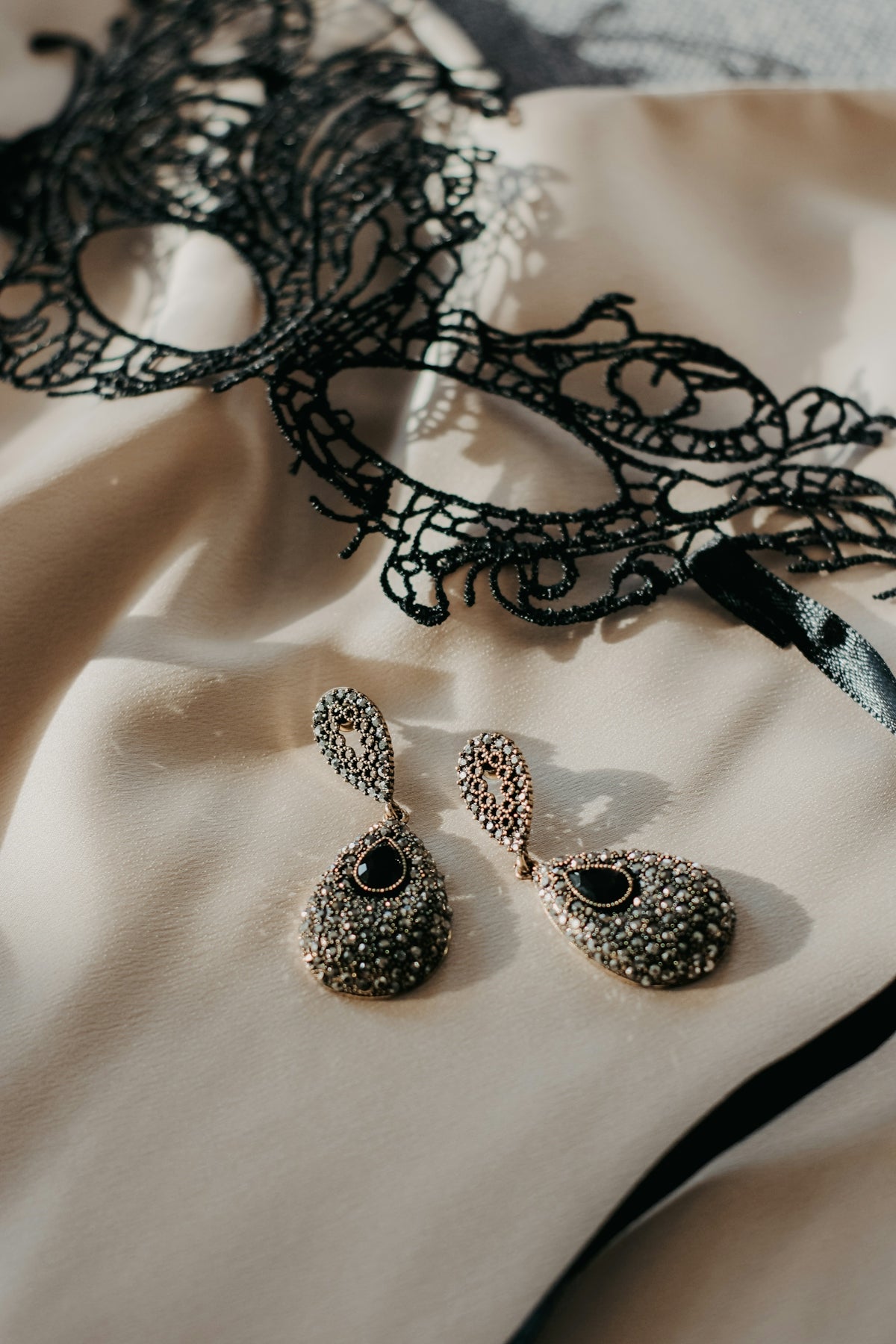 a masquerade mask and two pairs of earrings