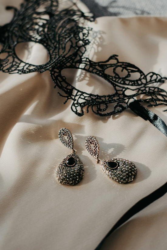 a masquerade mask and two pairs of earrings