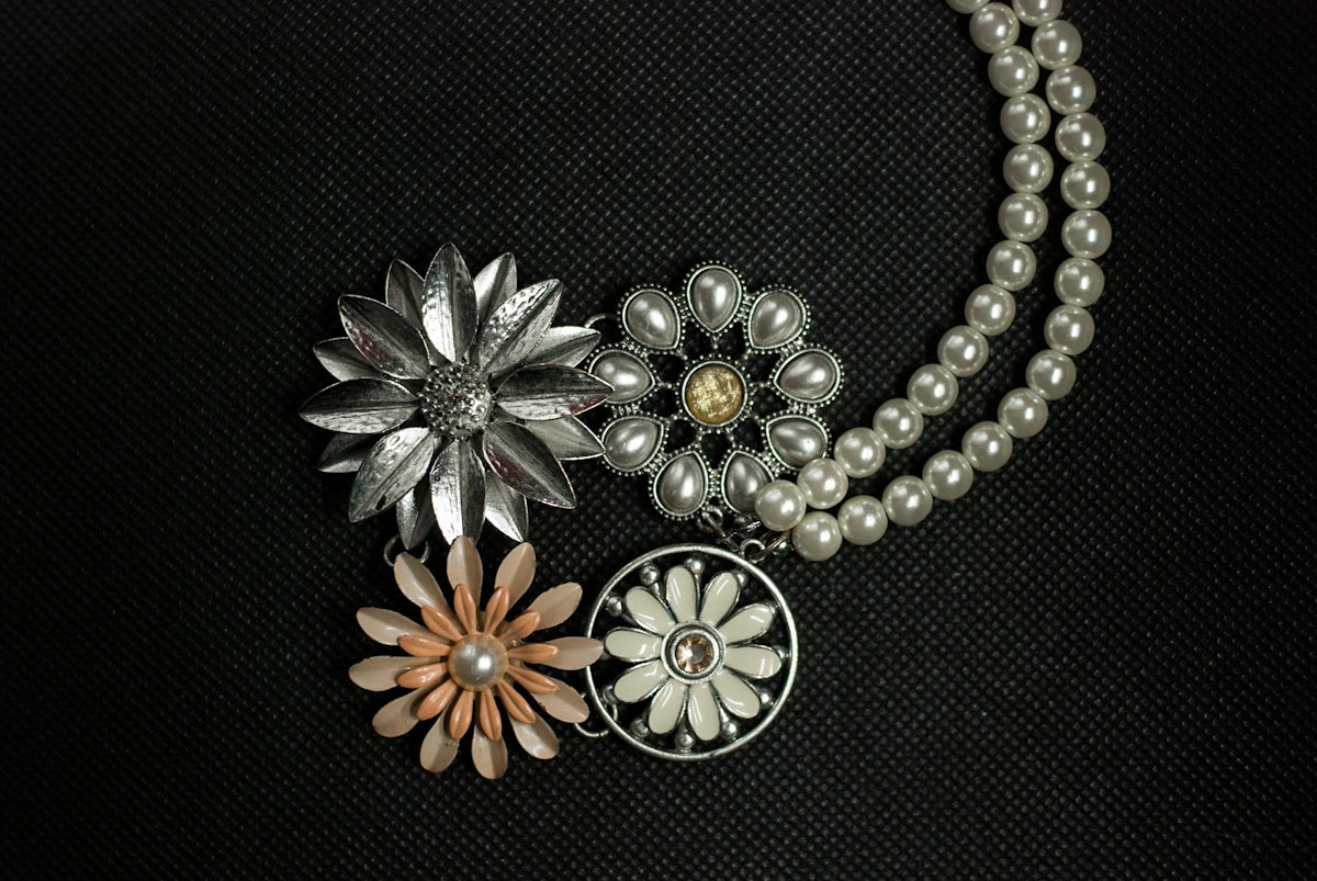 a close up of a necklace with flowers on it