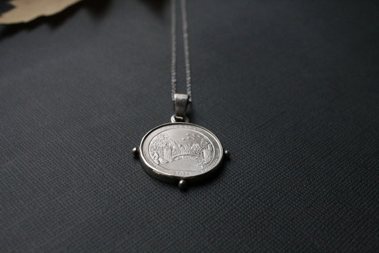 a small silver coin on a chain on a black surface
