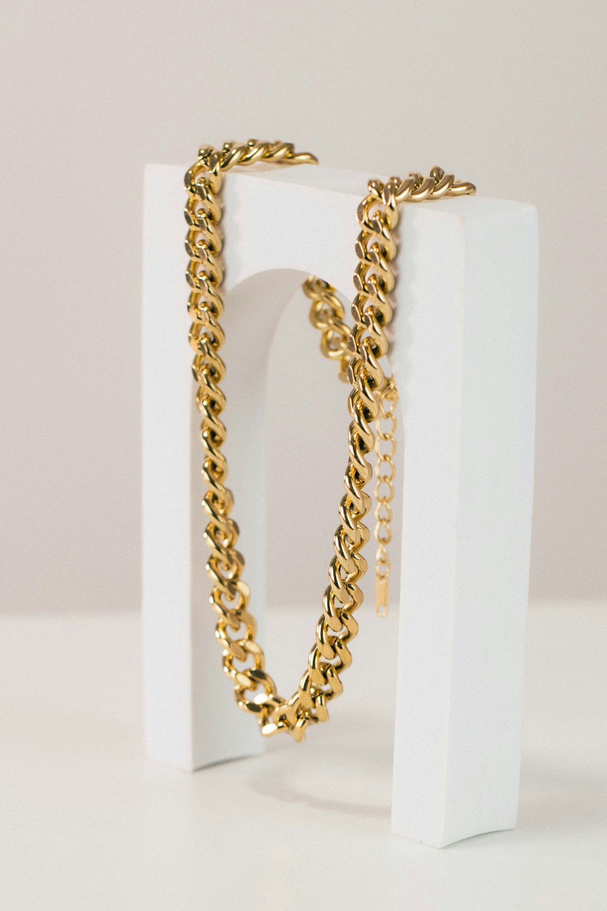 a pair of gold chain bracelets sitting on top of a white box