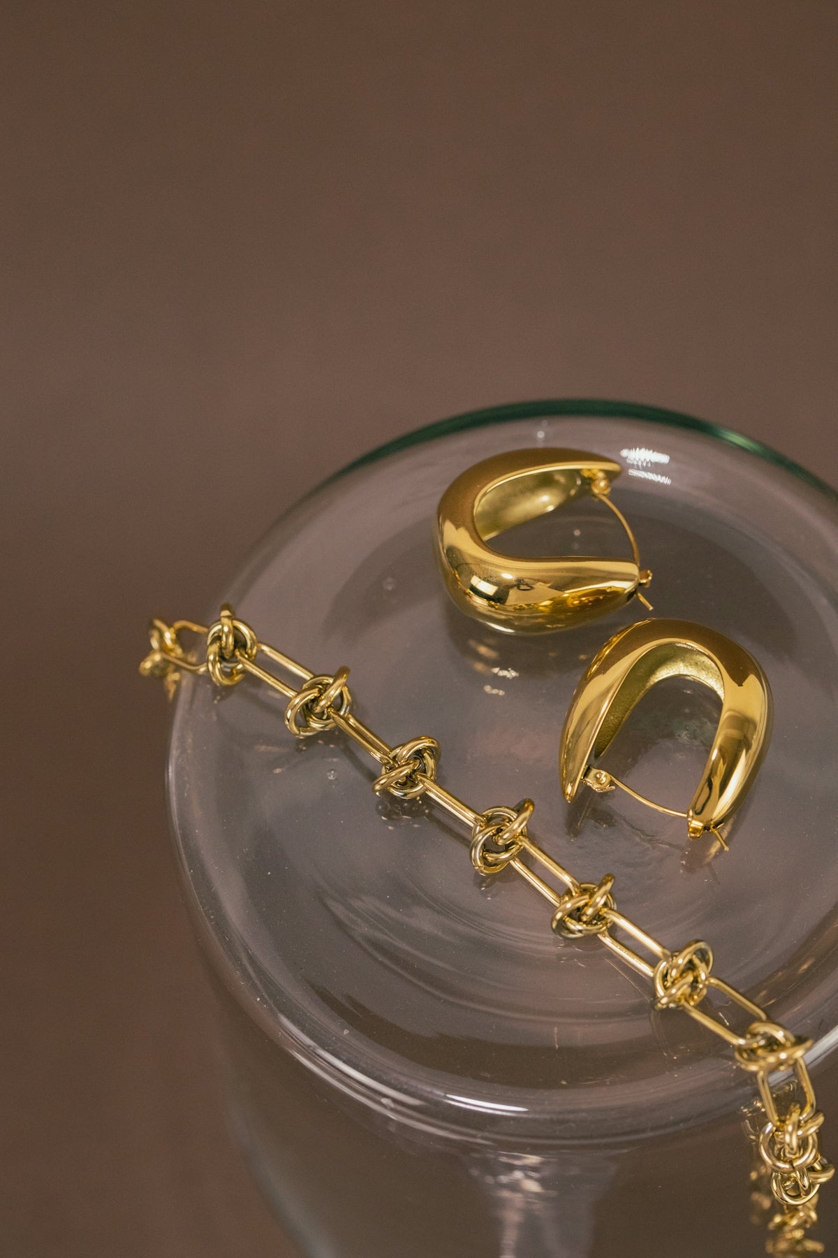 a pair of gold earrings sitting on top of a glass bowl