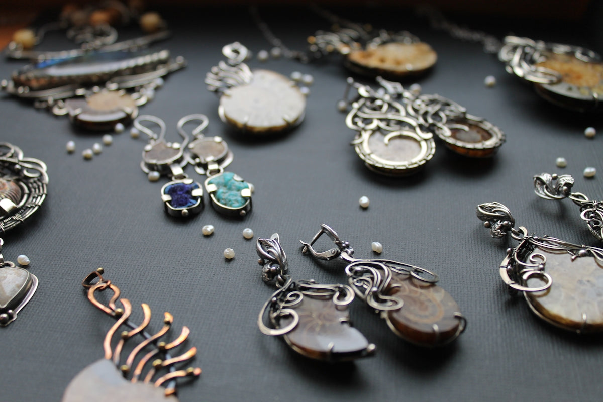 a table topped with lots of different types of necklaces