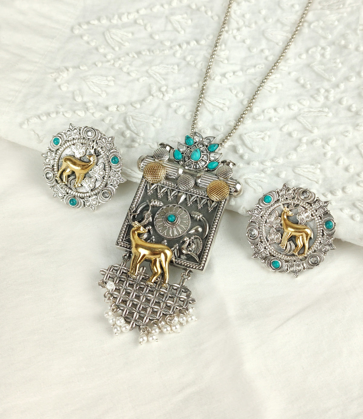 three pieces of jewelry sitting on top of a bed