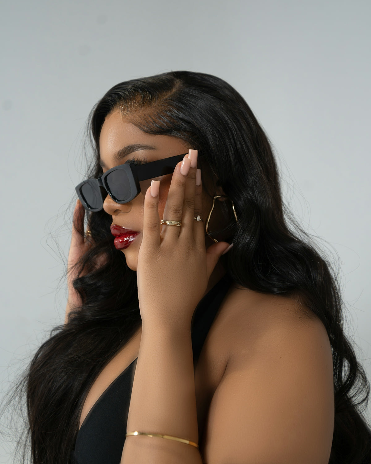 A woman in a black dress holding a pair of sunglasses