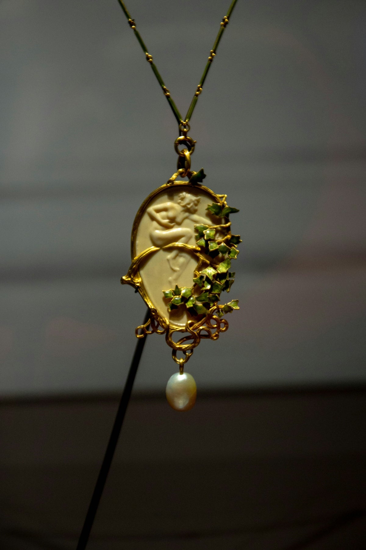 A gold necklace with a pearl hanging from it