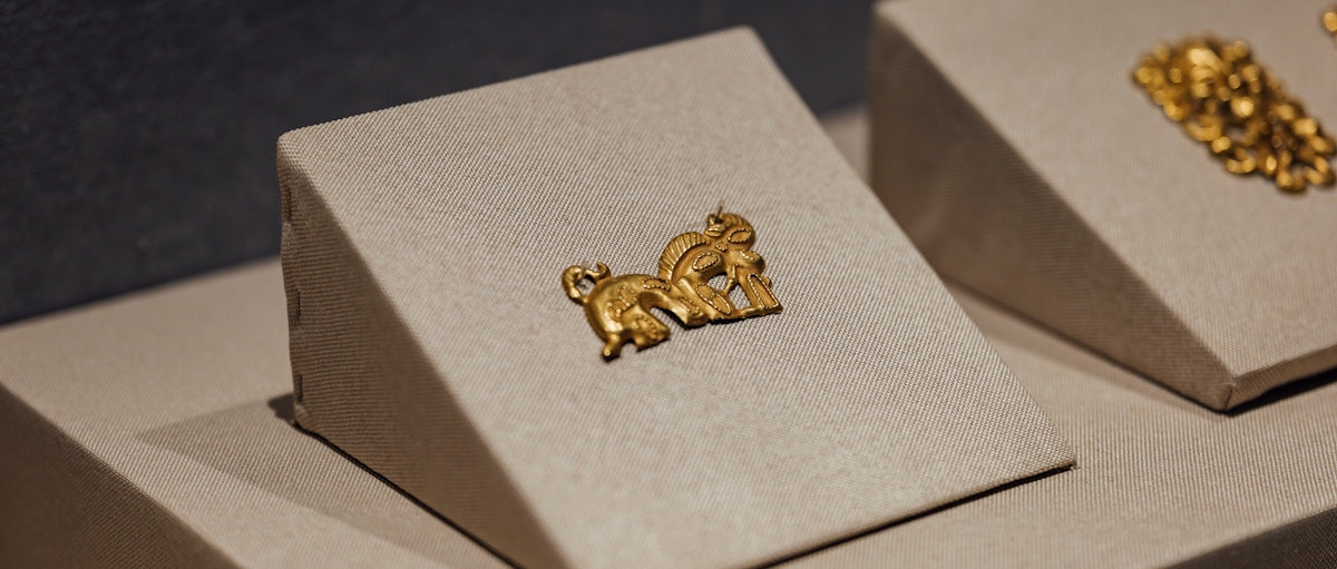 A pair of gold earrings sitting on top of a white box