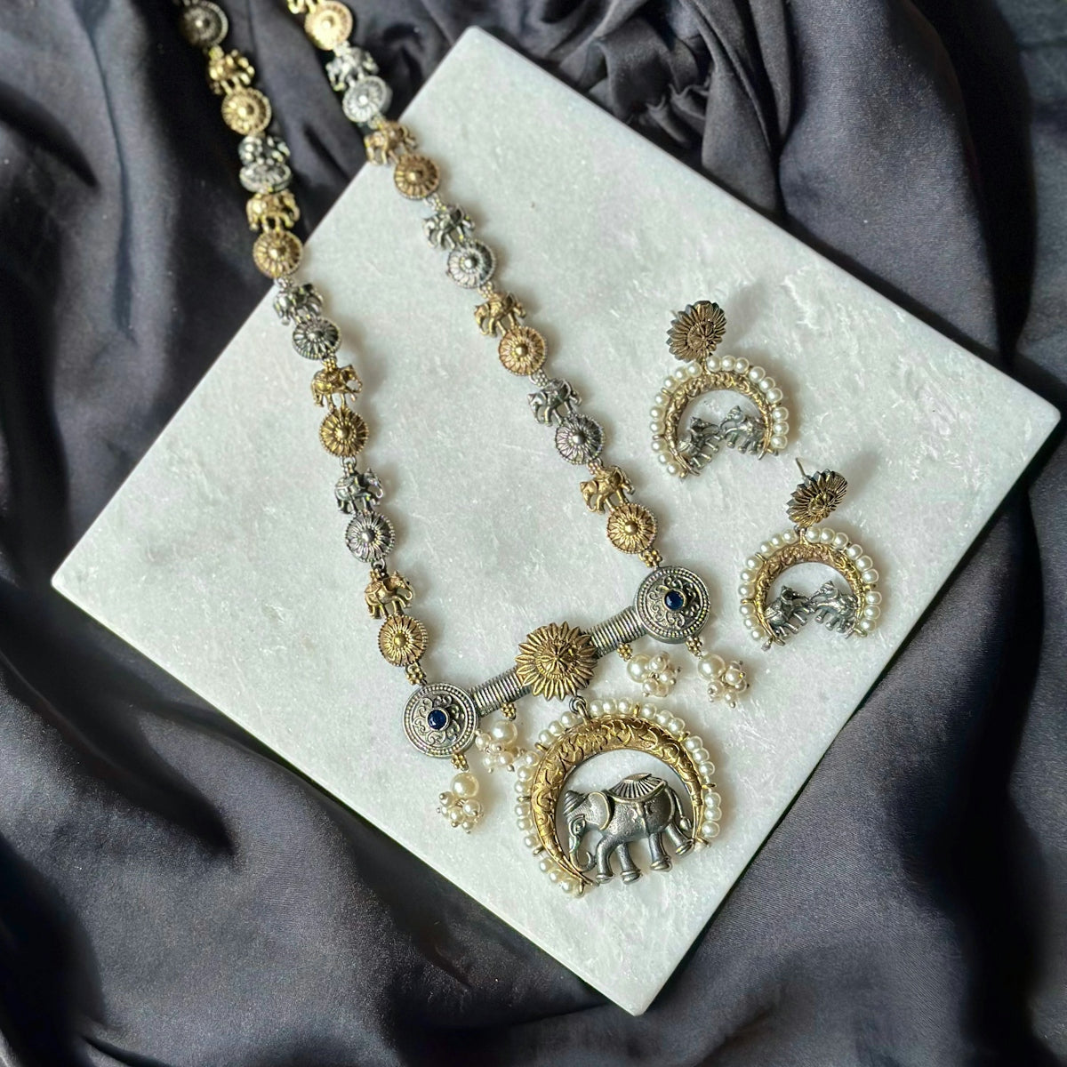 A necklace and earring set sitting on a cloth