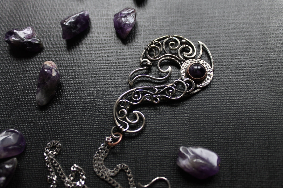 A decorative pendant is surrounded by amethyst gems.
