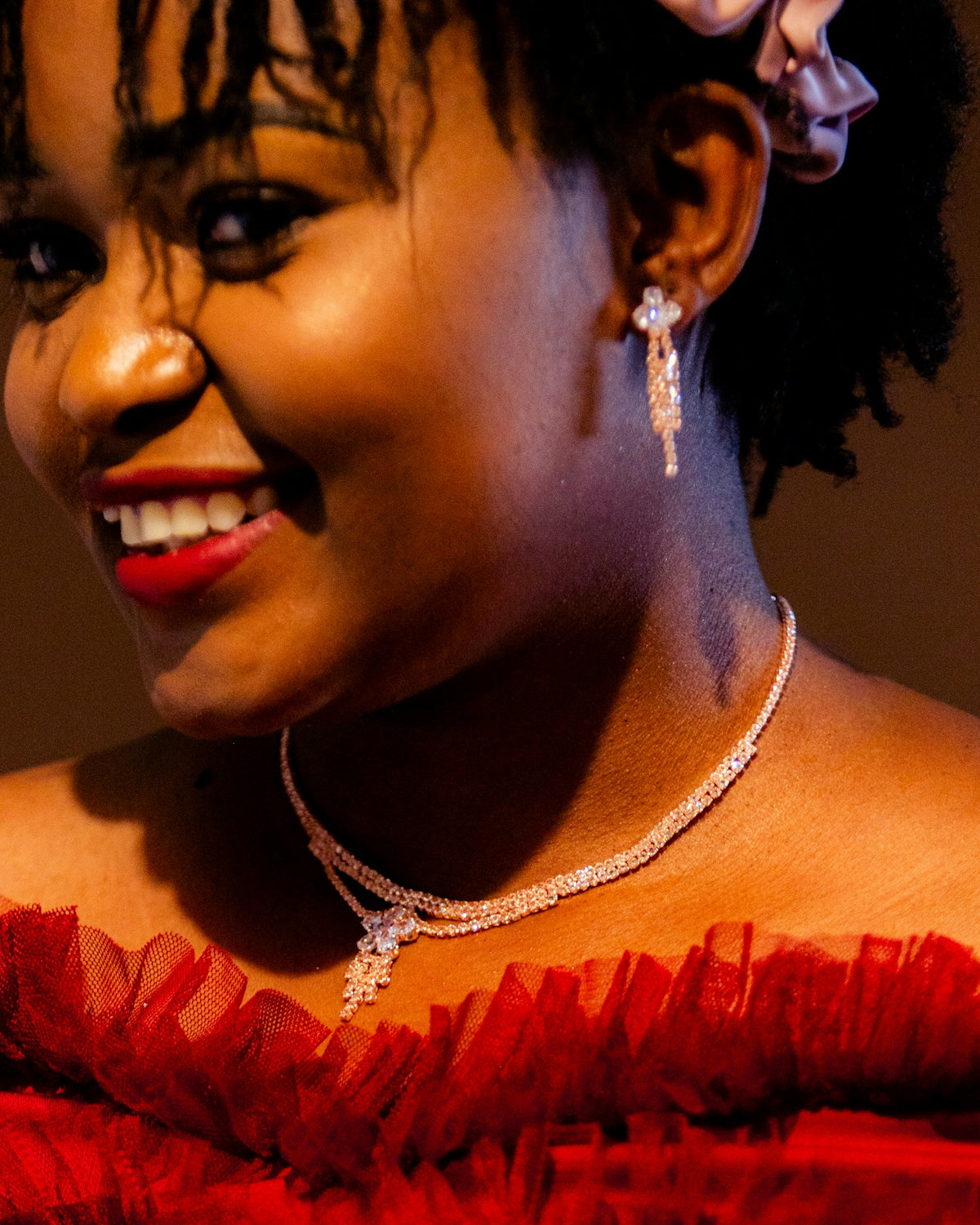 Elegant woman smiles, adorned in jewelry.