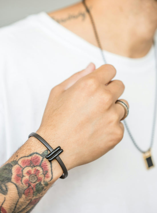 A man shows off his jewelry and tattoos.
