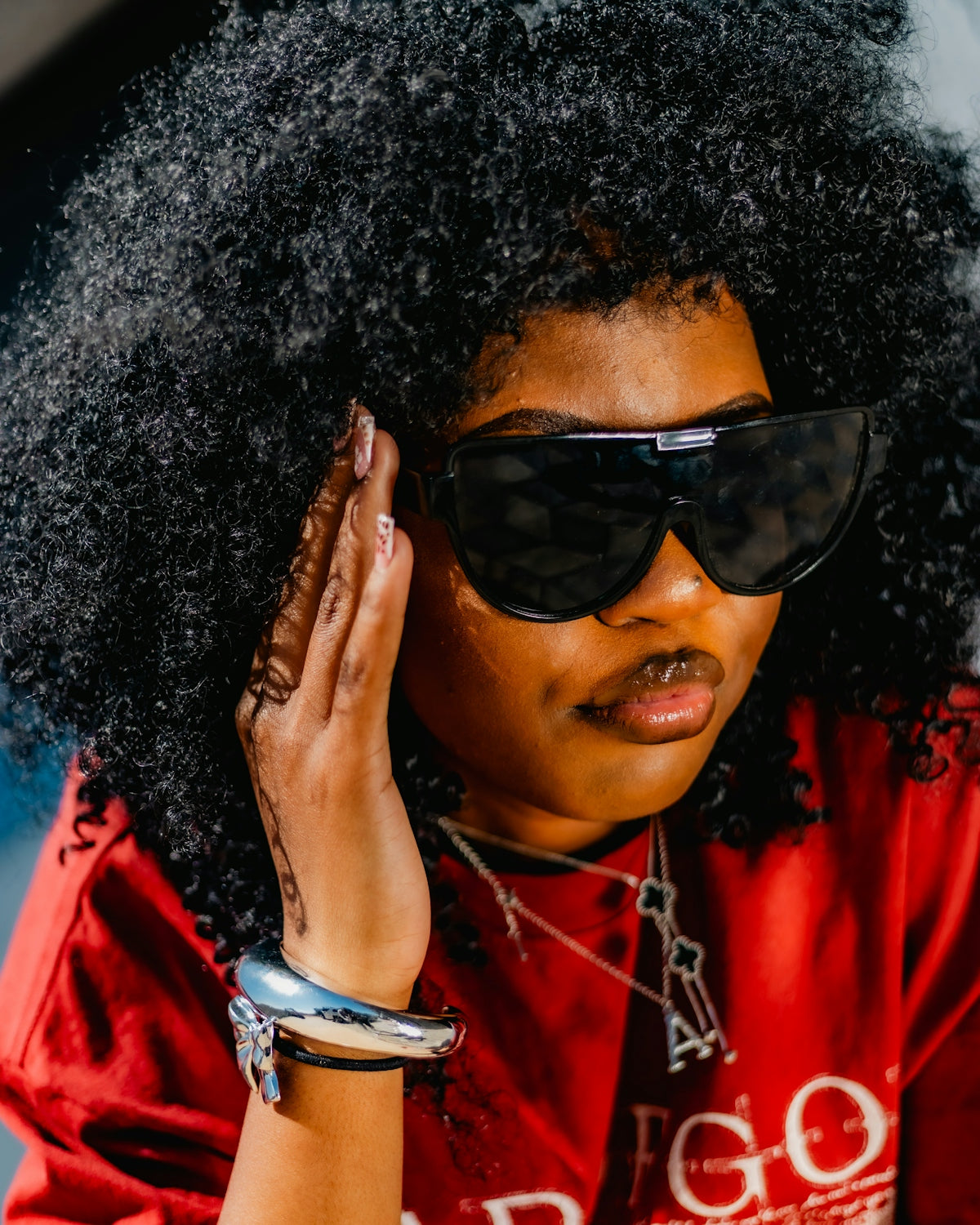Woman with large afro and sunglasses wearing red shirt