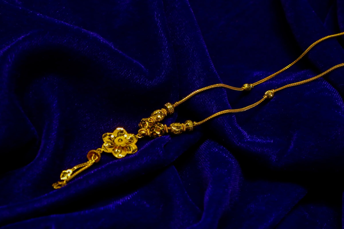 Gold floral pendant necklace on blue fabric
