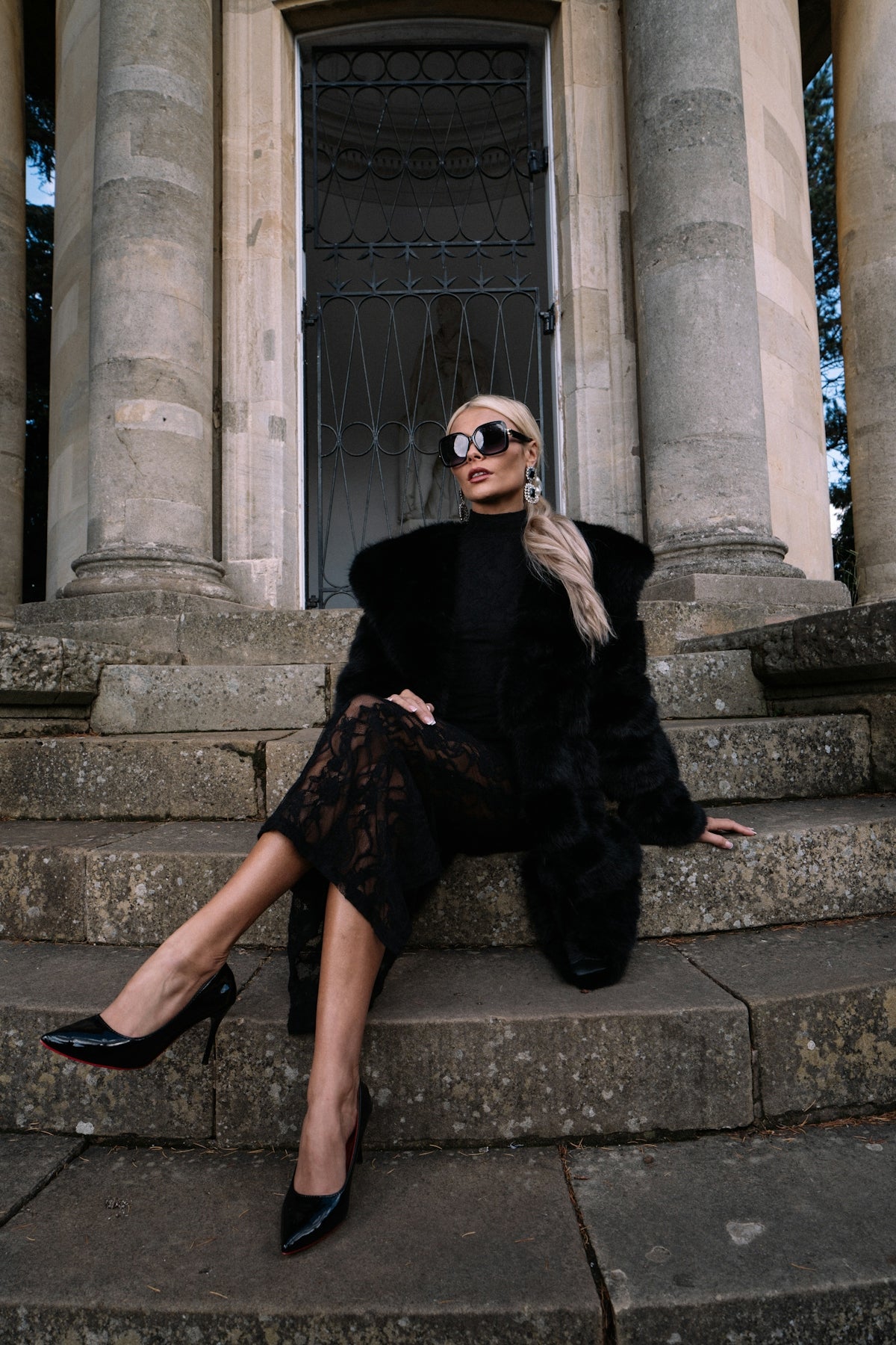 A woman in a black outfit sits on stone steps.