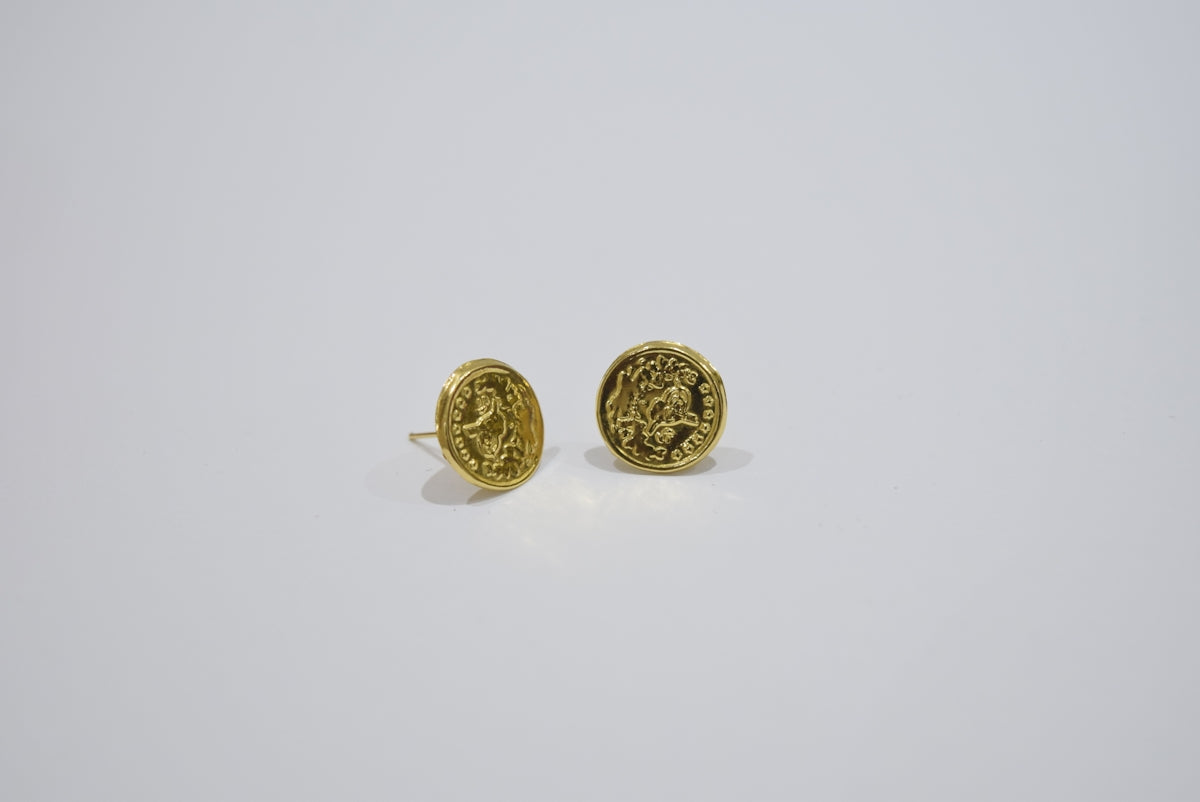 Two gold oval earrings with intricate designs.