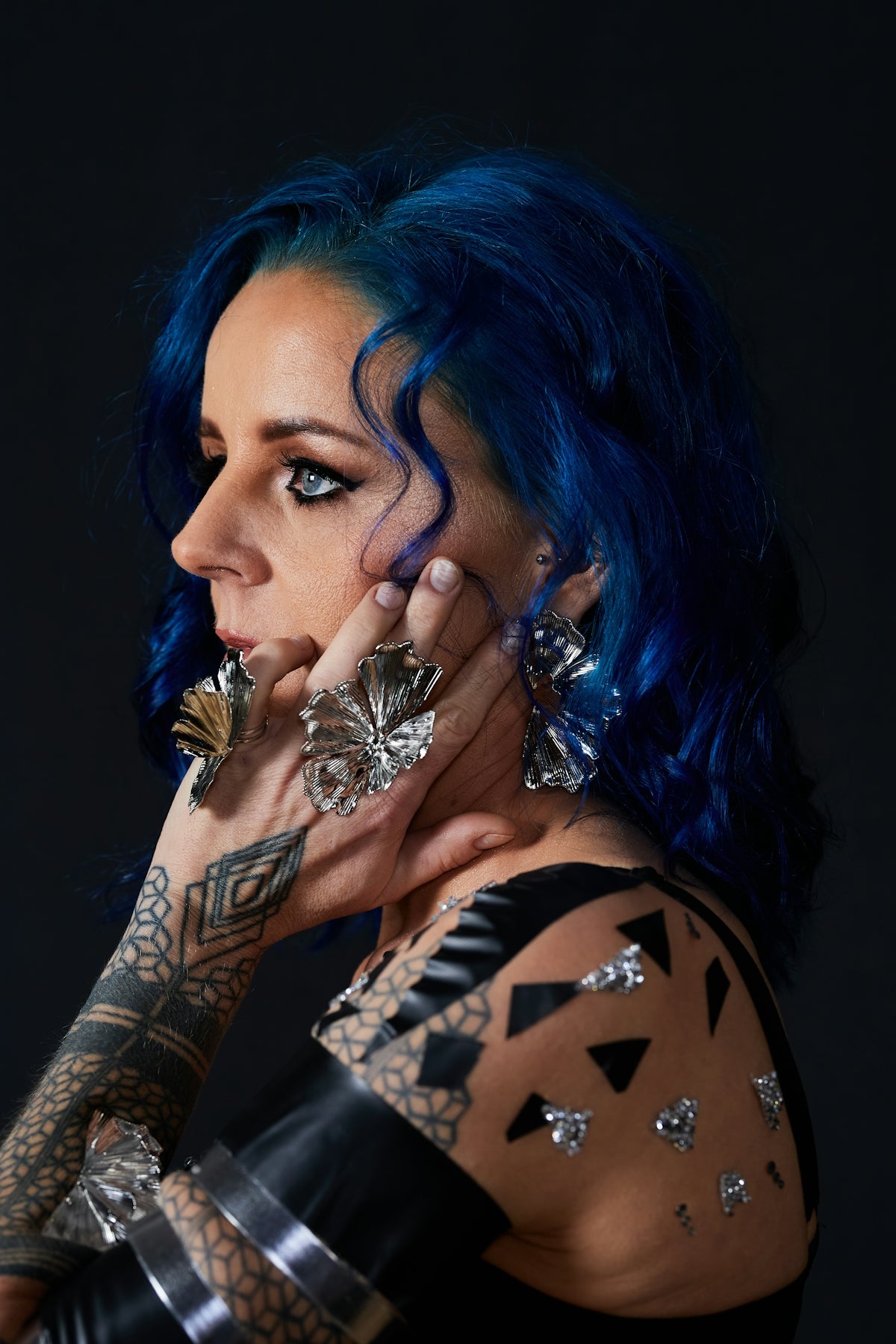 Woman with blue hair and large silver jewelry
