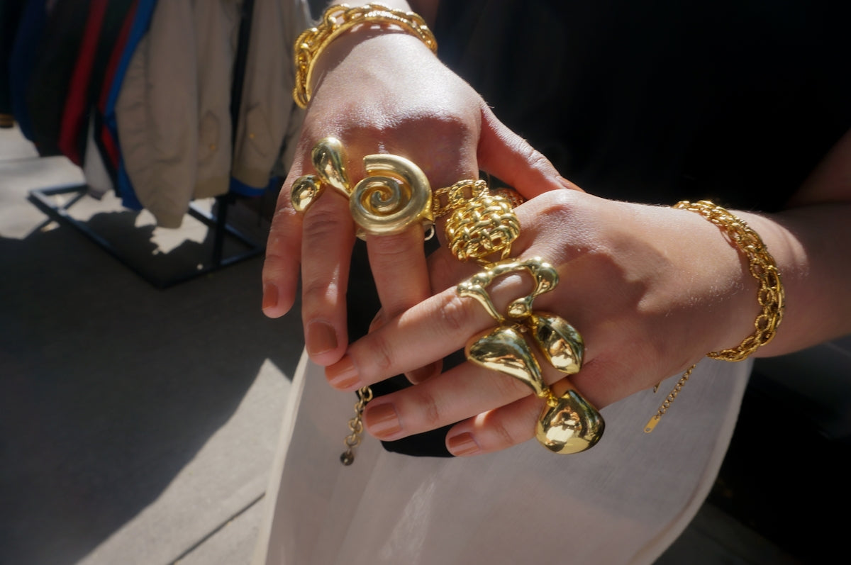 Hands adorned with chunky gold rings and bracelets.