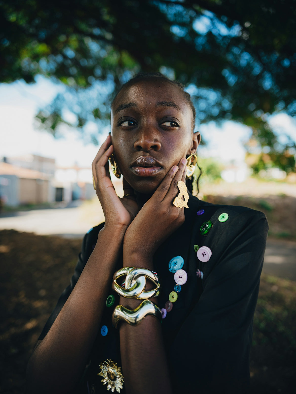 A person with striking jewelry and makeup looks thoughtfully.