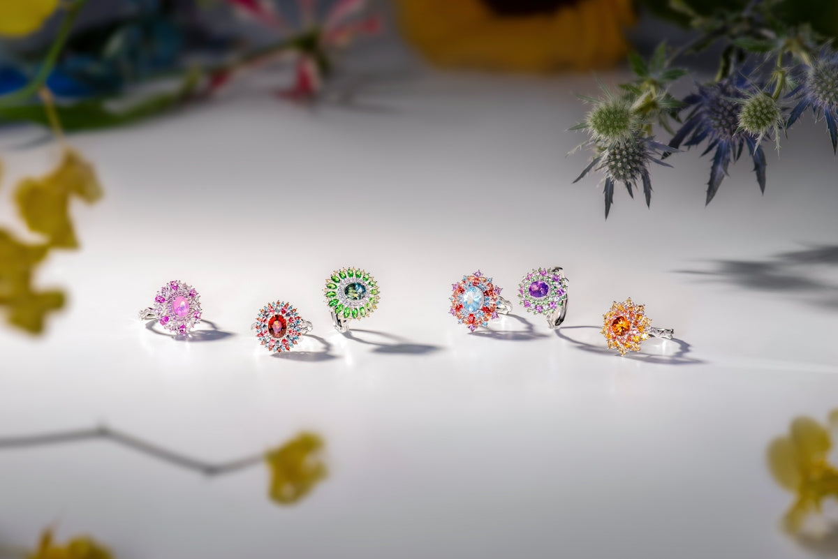 Assortment of colorful gemstone rings on a white surface.