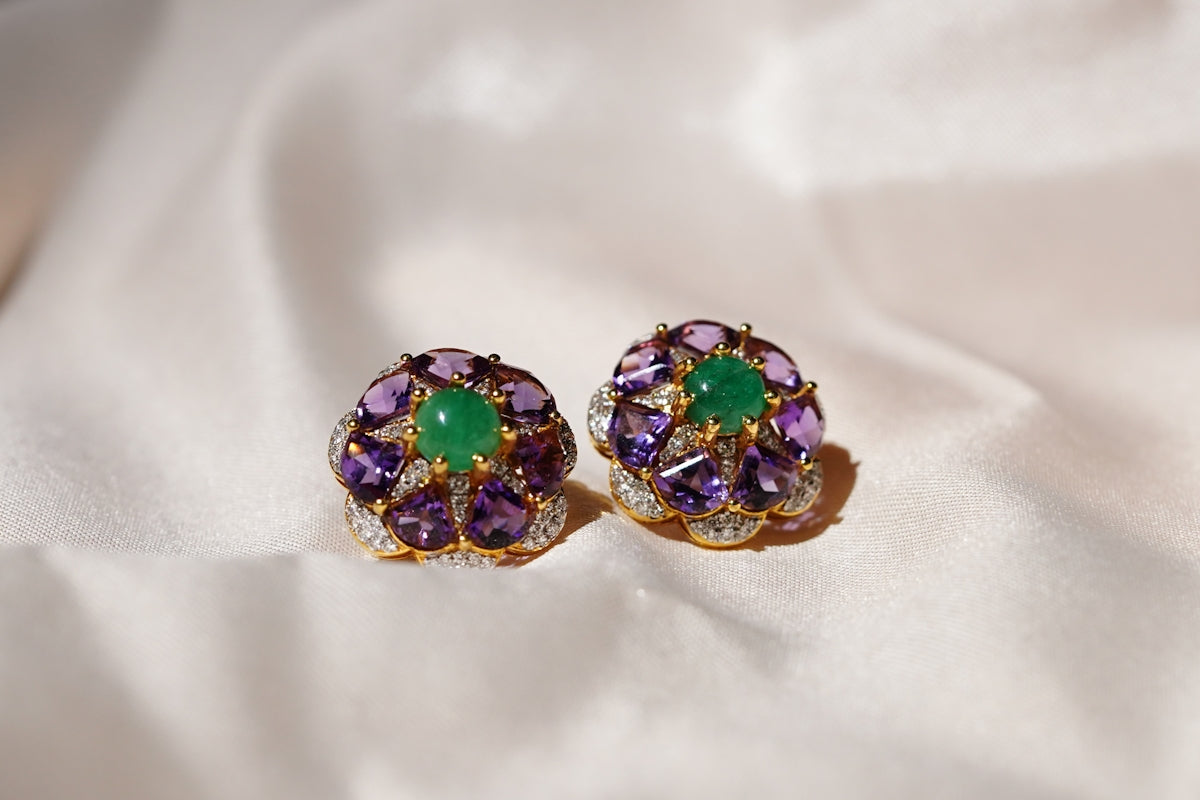 A pair of ornate earrings with green and purple gemstones.