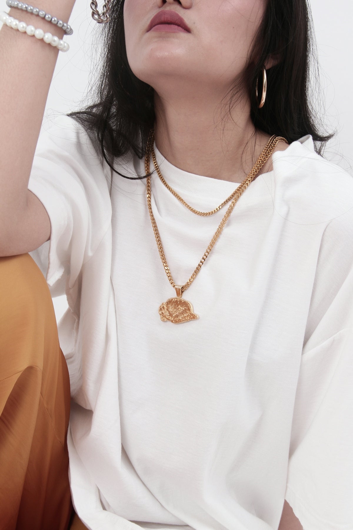 A woman wearing a white t-shirt and gold jewelry.