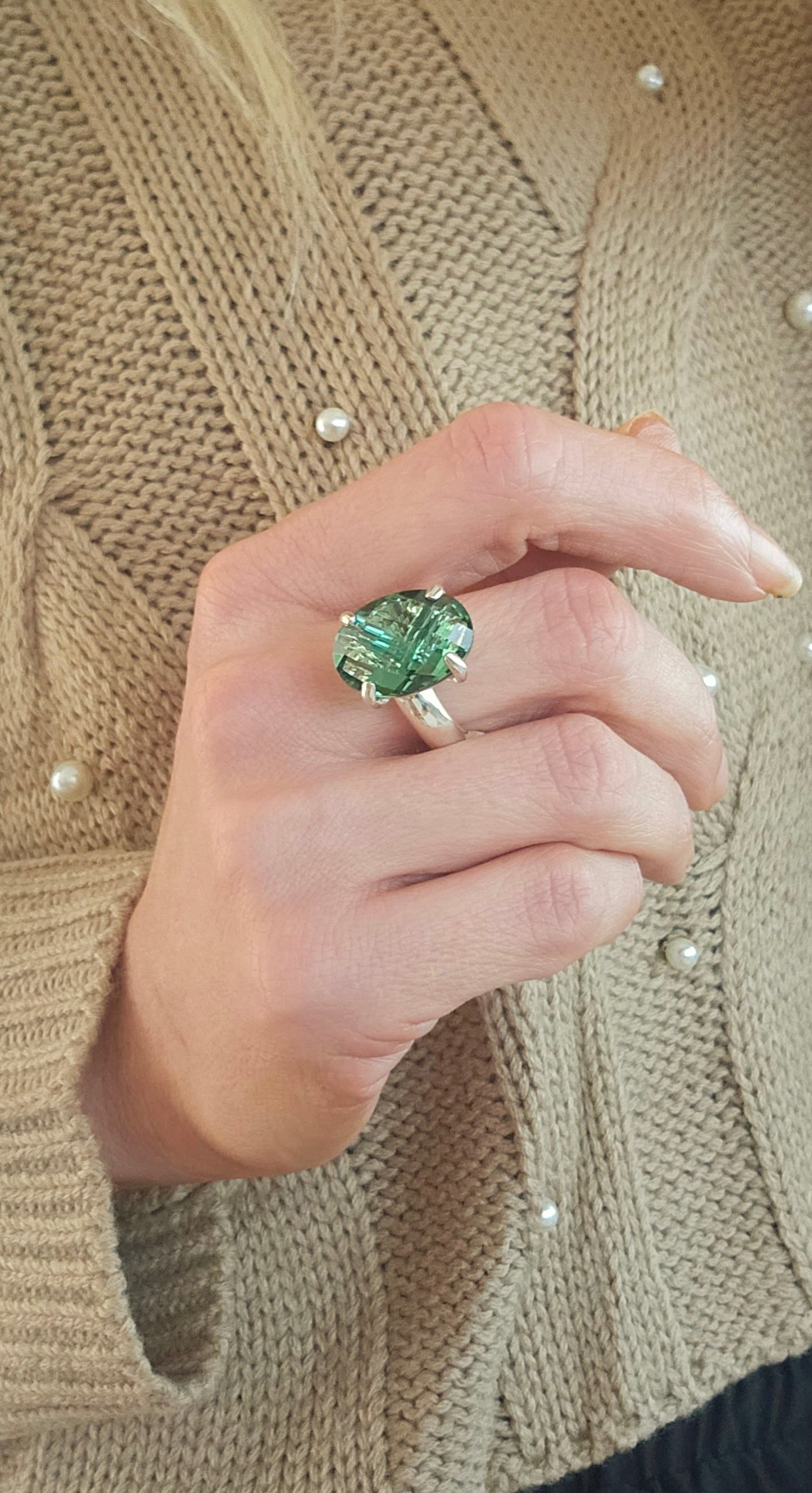 Green Faceted Quartz Ring set in solid sterling silver on a hand of a women wearing a pearl brown sweater. 